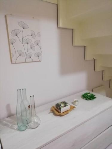 a white table with vases and a picture on the wall at Casa Sambuco in Volla