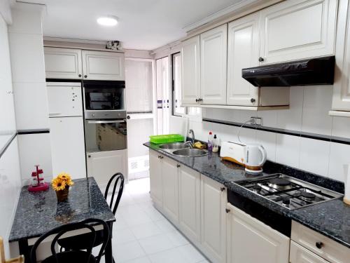 une cuisine avec des placards blancs et un comptoir noir dans l'établissement La Rose, à Gandía