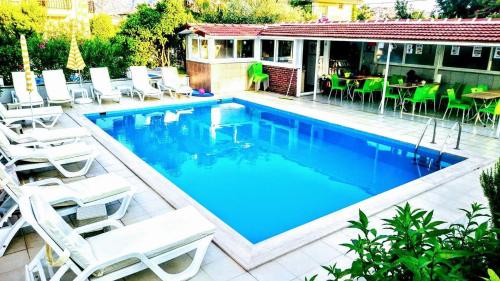a swimming pool with white chairs and a table at Karaca Apart Hotel in Dalyan