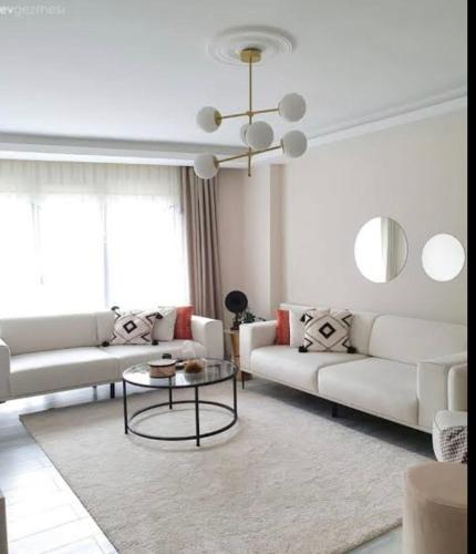 una sala de estar con sofás blancos y una mesa. en diana apartman en Şekerpınarı