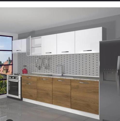 una cocina con armarios blancos y electrodomésticos de acero inoxidable en diana apartman en Şekerpınarı