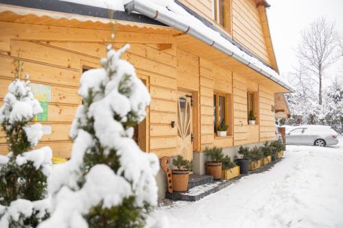 a wooden cabin with snow on the side of it at Apartamenty Zakopiańska Polana in Zakopane