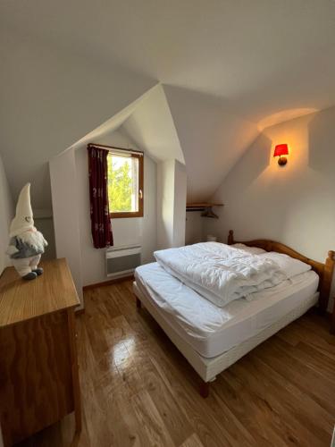 um quarto com uma cama branca e uma janela em T3 duplex Super Besse, parking, piscine, wifi em Besse-et-Saint-Anastaise