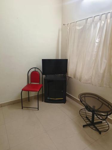 sala de estar con silla roja y TV en Flagship La Grande Residencya en Old Goa