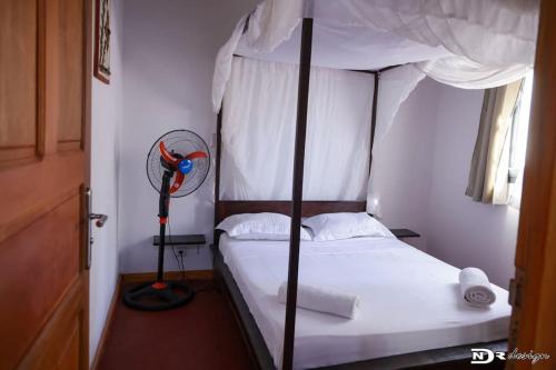 1 dormitorio con cama con dosel y ventilador en Maison « tsarajoro »3ch majunga, en Mahajanga