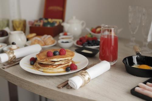 a table with a plate of pancakes and berries on it at UNA HOTELS Tenuta Contessa Farm & SPA Cosenza in Montalto Uffugo