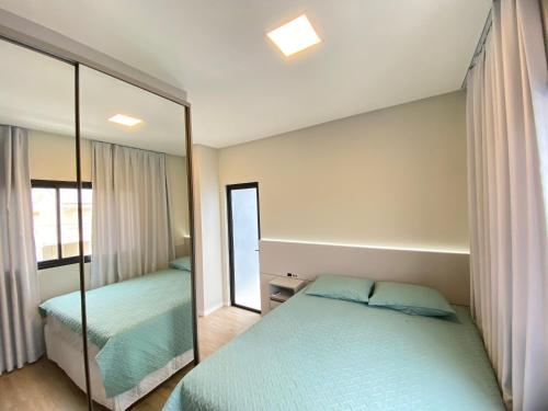 een slaapkamer met twee bedden en een spiegel bij Bellacasa Rua Leão in Bombinhas