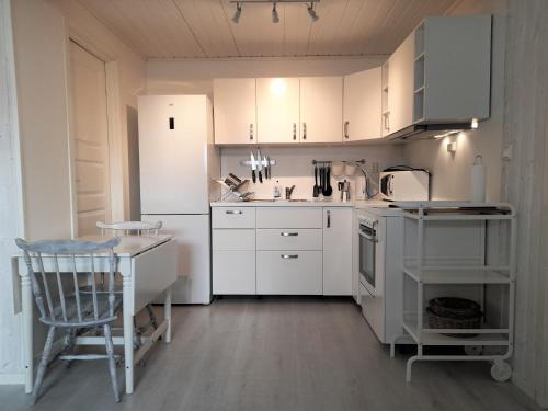 a kitchen with white cabinets and a table and a chair at Olderdalen Ski Camp in Olderdalen
