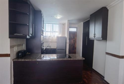 een keuken met zwarte kasten en een zwart aanrecht bij Lela Holiday Apartments in Durban