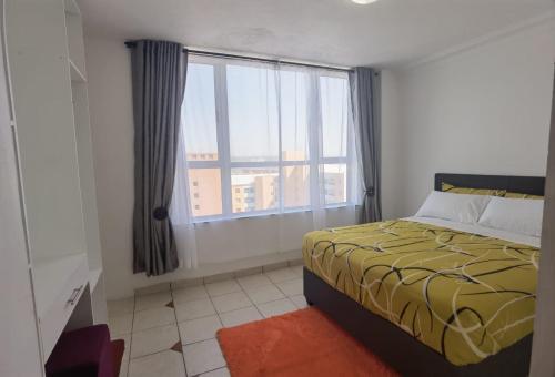 een slaapkamer met een bed en een groot raam bij Lela Holiday Apartments in Durban