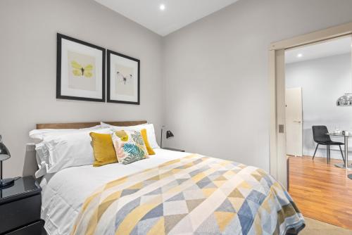 een slaapkamer met een bed met gele en blauwe kussens bij Notting Hill: Stylish 1BR with Terrace - Suite Inn in Londen