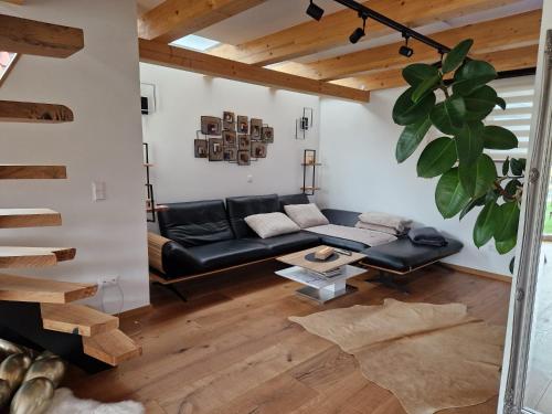 a living room with a black leather couch and wooden floors at FERIENHAUS A&C DELUXE AM SEE in Spielberg