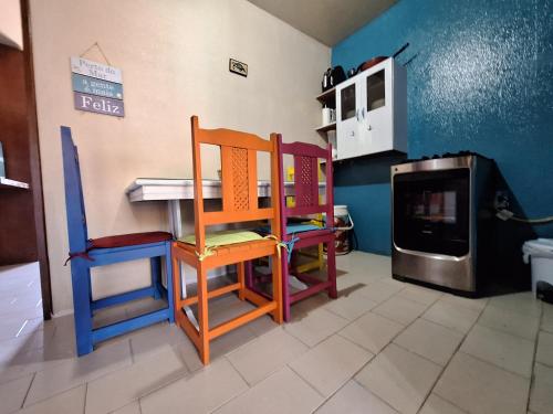 uma cozinha com cadeiras coloridas, uma mesa e um fogão em Praia Flat em São José da Coroa Grande