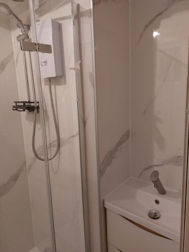 a white bathroom with a shower and a sink at Sea Air B&B in Chapel Saint Leonards