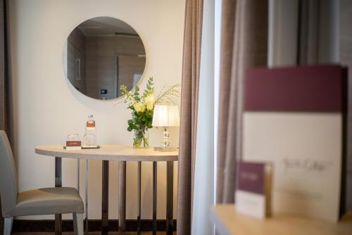 a table with a vase of flowers and a mirror at UNA HOTELS Tenuta Contessa Farm & SPA Cosenza in Montalto Uffugo
