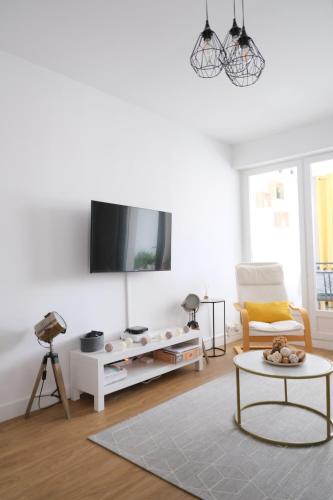 un salon avec une télévision sur un mur blanc dans l'établissement Appartement 3 pièces - Cabourg, à Cabourg