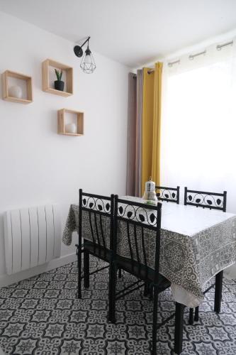 une table et des chaises dans une pièce avec une fenêtre dans l'établissement Appartement 3 pièces - Cabourg, à Cabourg