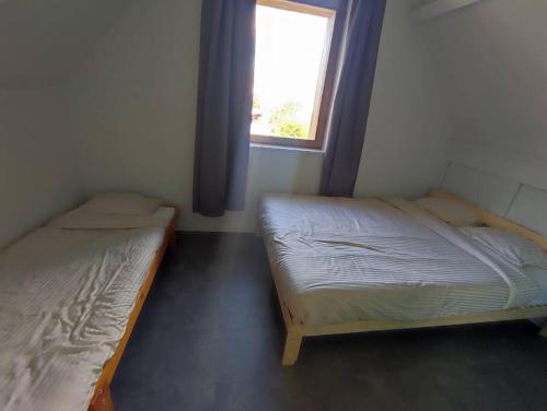 Duas camas num pequeno quarto com uma janela em Huis Belijn em Lokeren