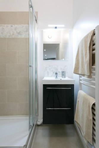 une salle de bain blanche avec une douche et un lavabo dans l'établissement Rose, Appartement Confortable proche Metro, à Montrouge