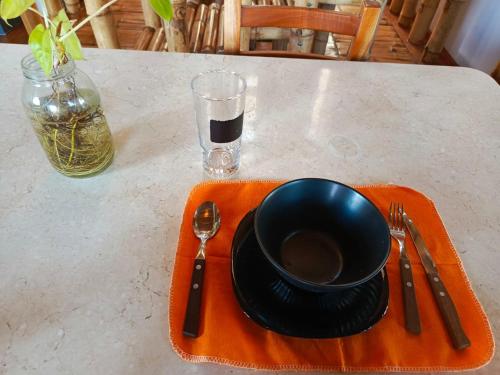 a black bowl and a plate on a table with a glass at Casa Bambú Galápagos in San Cristobal
