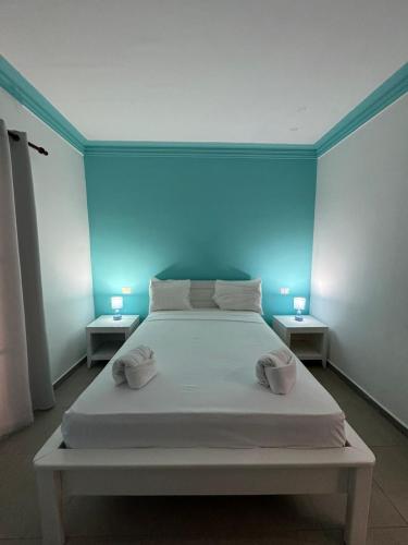 a bedroom with a white bed with a blue wall at Las Palmeras by Graziano in Boca Chica