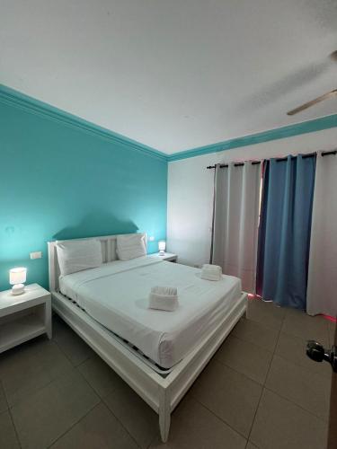 a bedroom with a large white bed with blue walls at Las Palmeras by Graziano in Boca Chica