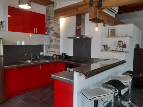 une cuisine avec des placards rouges et un comptoir dans l'établissement La Manufacture d'épaulettes, à Prades