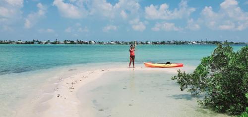 a woman standing on a beach next to a boat at Bonnethead Key Floating Campground and Private Island in Key West