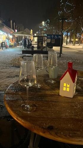 a table with three wine glasses and a small house on it at Rezidencia pod Zámkom Bojnice Apartmán Luna in Bojnice