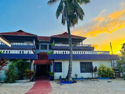 a building with a palm tree in front of it at WYNE'S COZY 2 BEDROOM IN SHANZU in Mombasa