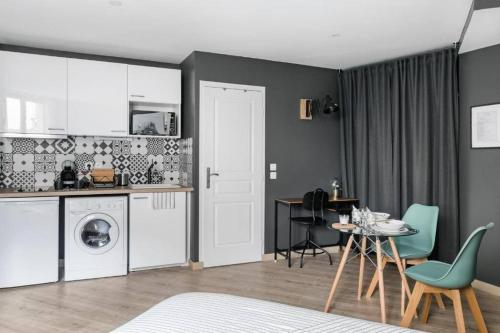 une cuisine avec un lave-linge, une table et des chaises dans l'établissement Lys : Cocon Douillet proche Métro, à Montrouge