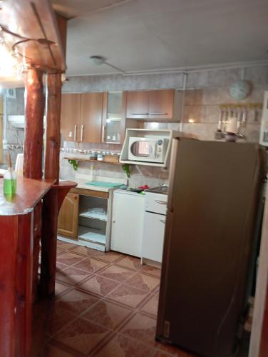 eine Küche mit einem Kühlschrank und einer Mikrowelle in der Unterkunft Casa cabaña My santy in Coihaique