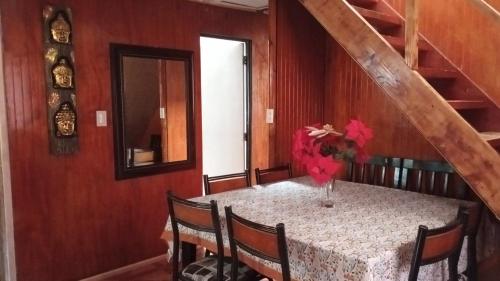 einen Esstisch mit einer Blumenvase darauf in der Unterkunft Casa cabaña My santy in Coihaique