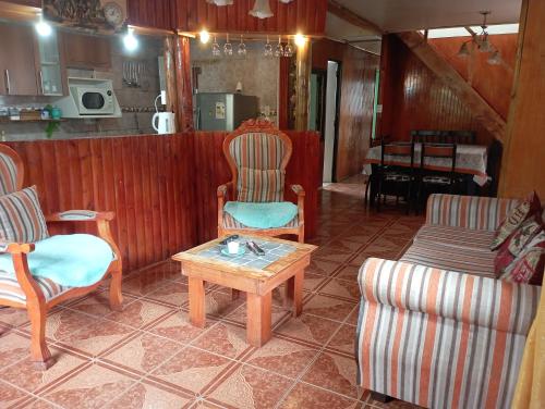 ein Wohnzimmer mit 2 Stühlen und einem Couchtisch in der Unterkunft Casa cabaña My santy in Coihaique