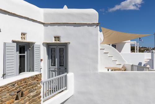 a white house with stairs and a blue door at Onar Hotel & Suites in Tinos Town