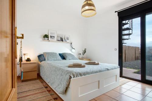 a white bedroom with a bed and a window at La Casita de Majanicho in La Oliva