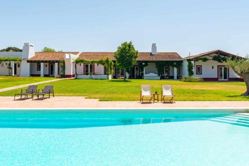a pool with chairs and a house in the background at Monte da Pedra Torta in Redondo