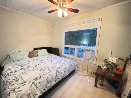 a bedroom with a bed with a ceiling fan and a window at Janis Lakeview Cottage 12-16 Guests in Wilberforce
