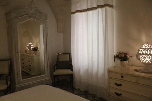 a bedroom with a dresser and a mirror and a chair at 'A Chesodde in Cisternino
