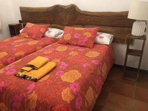 1 dormitorio con 2 camas, mantas y almohadas rojas y amarillas en Casa Rural La Cuadraá, en Linares de Riofrío