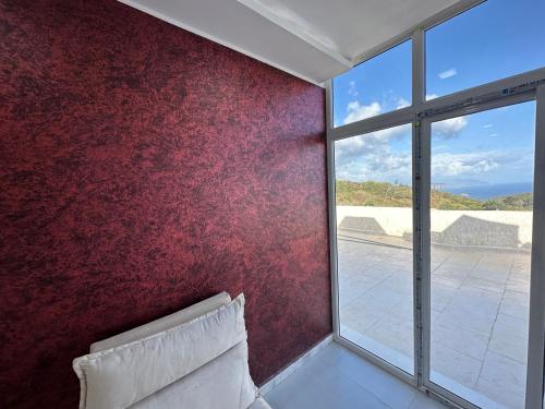 1 dormitorio con pared roja y ventana en Résidence plage Oued Tanger en Skikda