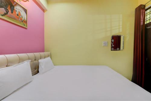 a bedroom with a white bed and a pink wall at Prayag Hotel & Restaurent in Naini