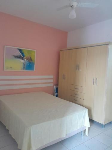 a bedroom with a white bed and a cabinet at Guarajuba Residence - Flat in Camacari