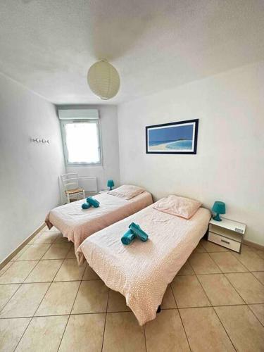 - 2 lits dans une chambre avec 2 serviettes dans l'établissement Sympa F2 avec parking et piscine, à Montpellier