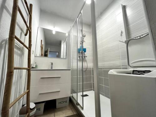 une salle de bain blanche avec une douche et un lavabo dans l'établissement Sympa F2 avec parking et piscine, à Montpellier