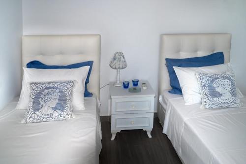 two beds with blue and white pillows and a night stand at Aelia Luxury Villa in Amoopi