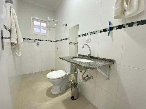 uma casa de banho branca com um lavatório e um WC em morada do sol em Ubatuba