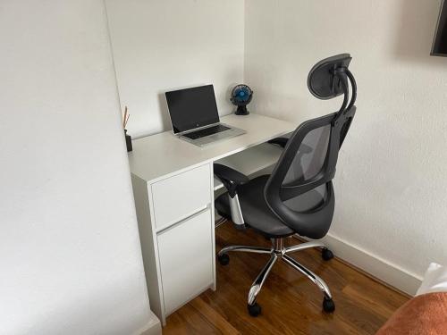 uma secretária com um computador portátil e uma cadeira num quarto em Hometel Nice Cute Apartment em Thornton Heath