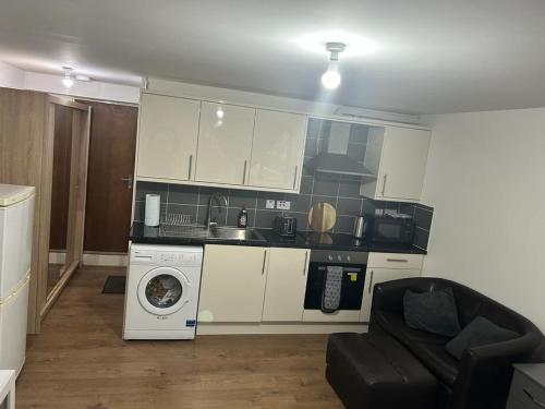 a kitchen with a washing machine and a microwave at Hometel Big Luxurious Self Contained Bedsit in Thornton Heath