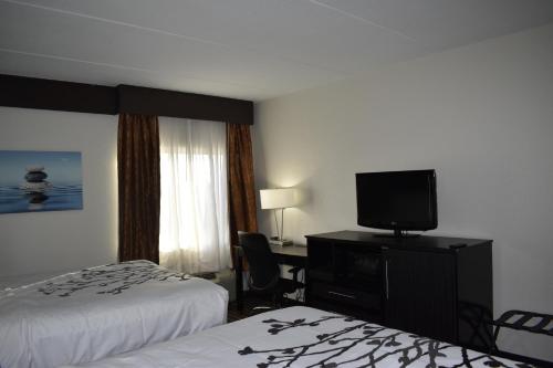 a hotel room with two beds and a flat screen tv at Sleep Inn & Suites West Knoxville in Knoxville